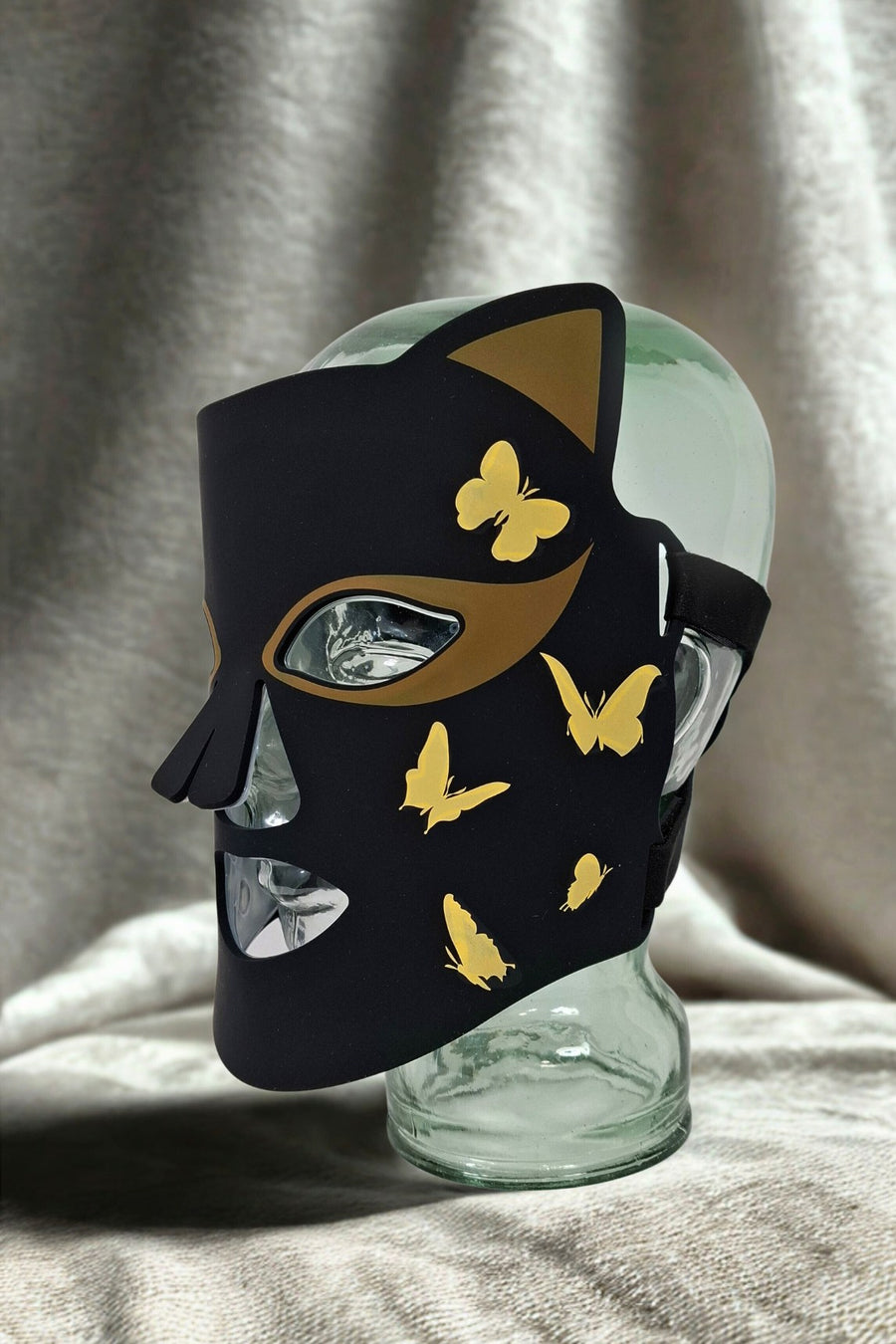 glamour Masque LED ONËRA Glam Cat noir et doré présenté sur tête en verre, appareil de luminothérapie visage au design élégant inspiré des soins esthétiques en institut haut de gamme